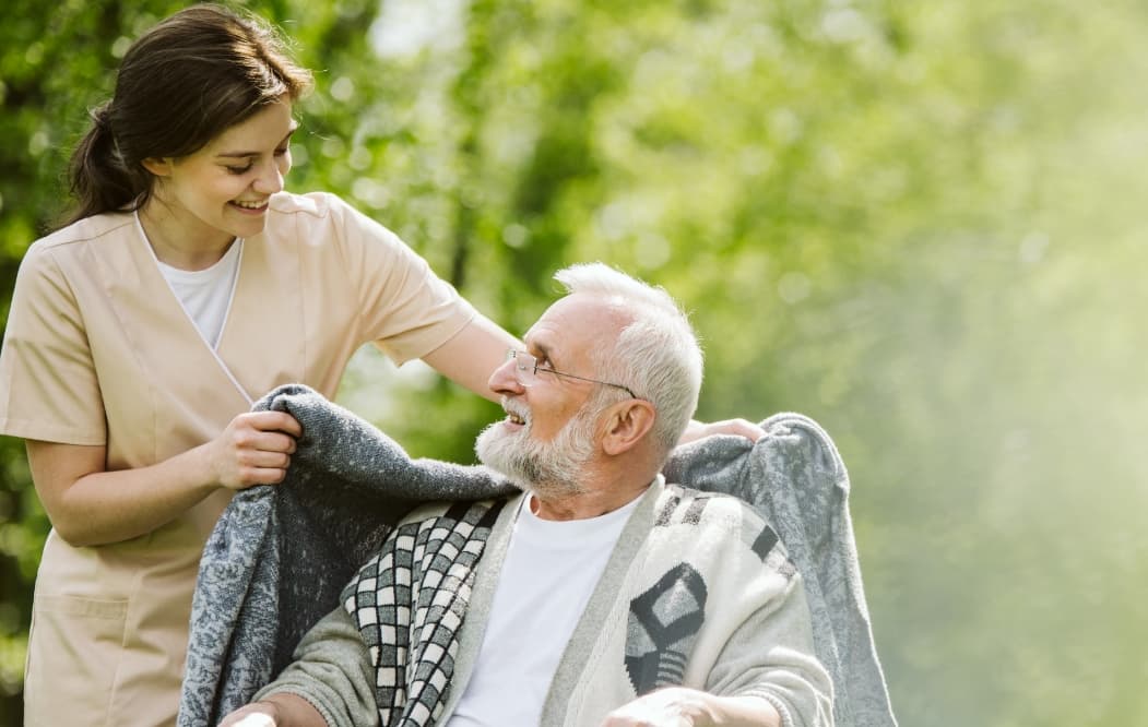 Assisted living staff giving a man a blanket.